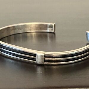 Silver bracelet with black wire ribbons.